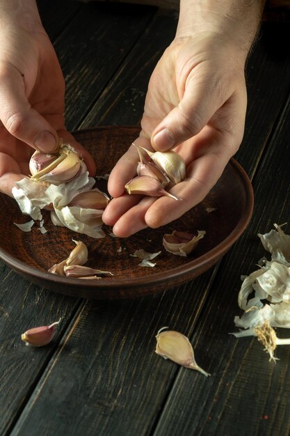 Foto pulizia chasnok dalle mani di uno chef nella cucina del ristorante