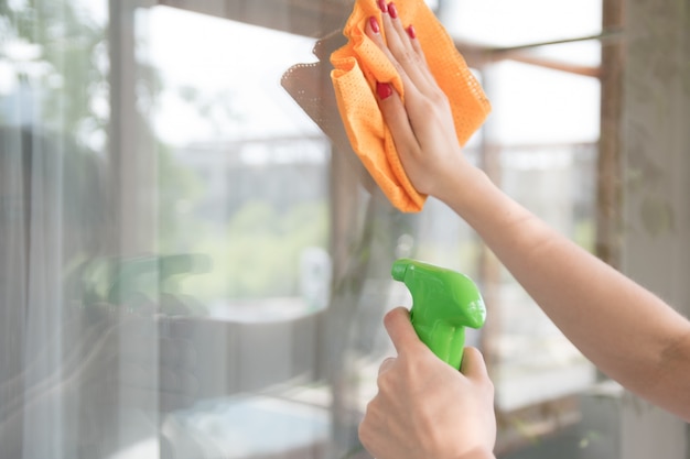 清掃会社が窓の汚れをきれいにします。主婦は家の窓をクリーナーで磨く