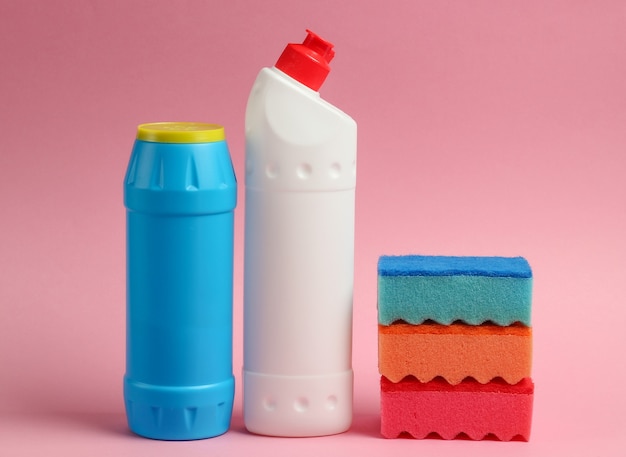 Cleaning concept. Detergent bottles, sponges on pink pastel background