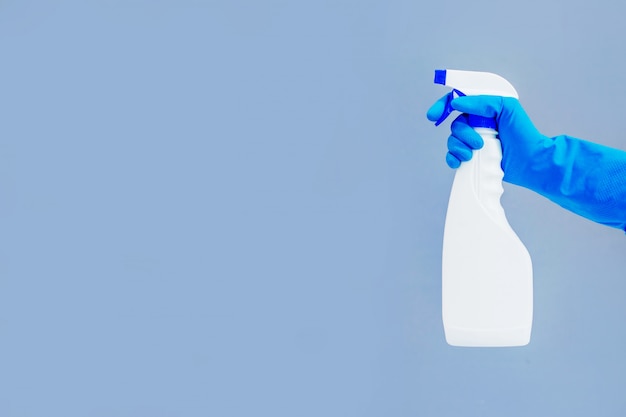 Cleaning concept gloves, spray with detergent  on blue background.