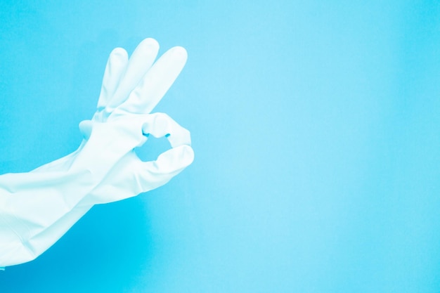 Cleaning concept Hand in medical gloves with doing ok symbol isolated on light blue background