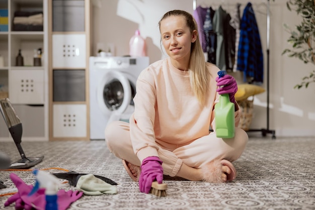 Cleaning concept at home a woman sits on the bathroom floor in the laundry room scrubbing floor