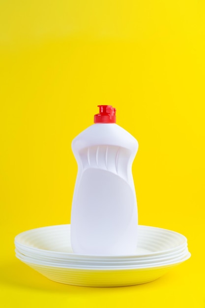 Cleaning detergent for dishes on a white plates on a yellow background Top view cleaning company