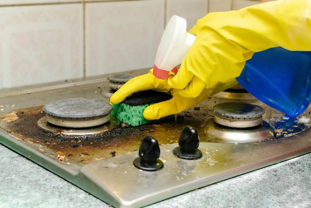 Foto pulire la stufa a gas sporca dal grasso, gli avanzi di cibo, depositare la mano nel guanto spugna detergente