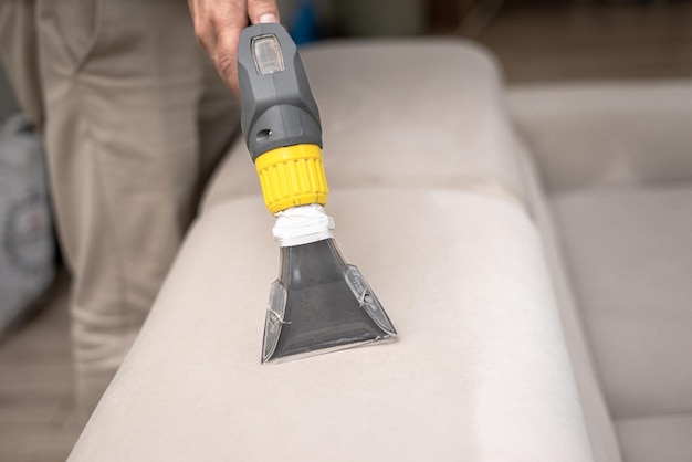 Cleaning a dirty sofa with a sofa washer Close up of hands holding sofa cleaner Professional sofa wash Sofa wash image