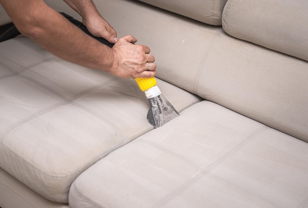 Cleaning a dirty sofa with a sofa washer Close up of hands holding sofa cleaner Professional sofa wash Sofa wash image