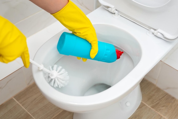 Cleaning and disinfection of toilets Cleaner in yellow rubber gloves cleans the toilet with a brush