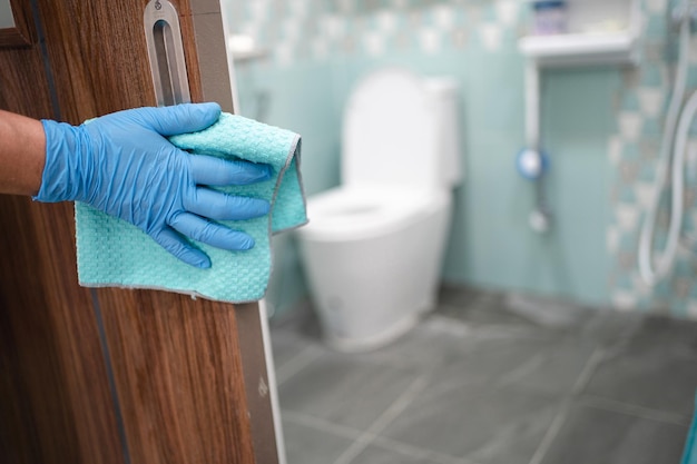 写真 covid19コロナウイルスを保護するためにオフィスと家庭でアルコールと柔らかい布でトイレのドアtolietハンドルを掃除する