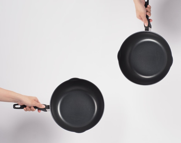 Cleaning Electric non stick pan. Hand on white background cleaning the non stick pan with handy dish washing sponge which yellow color on the soft side and green on hard side for hygiene after cook.