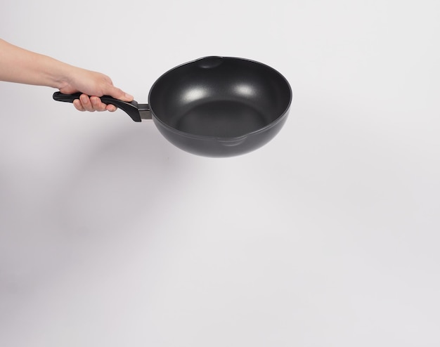 Cleaning Electric non stick pan. Hand on white background cleaning the non stick pan with handy dish washing sponge which yellow color on the soft side and green on hard side for hygiene after cook.