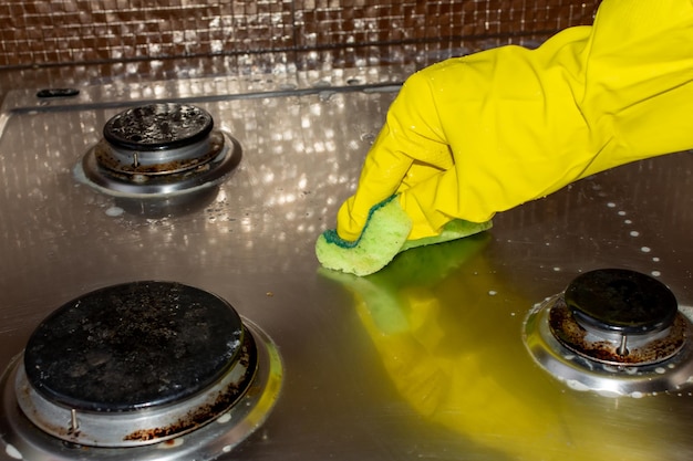 Cleaning the gas stove from dirt with a green sponge