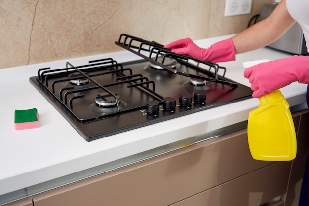 Cleaning a gas stove with kitchen utensils, household concepts, or hygiene and cleaning.