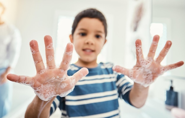 Photo cleaning hands with soap and boy in bathroom for hygiene wellness and healthcare at home healthy family skincare and portrait of child with open palms washing with water soap and disinfection