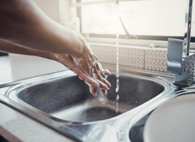 Cleaning health or washing hands in kitchen with soap for skincare self care or hygiene with tap water Safety zoom or healthy person at a sink for liquid protection against bacteria after cooking