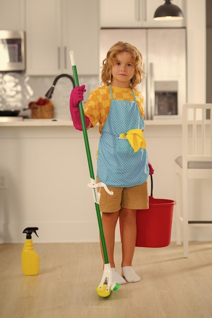 Photo cleaning at home little kid cleaning at home child doing housework having fun portrait of child housekeeper with wet flat mop on kitchen interior background