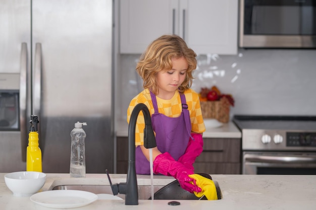 Фото Уборка дома маленькая экономка ребенок моет и вытирает посуду на кухне американский ребенок учится d