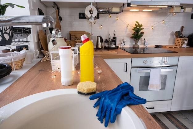 Photo cleaning the kitchen before the christmas and new year holidays detergent dry powder sponge gloves are on the sink festive decor in the white kitchen cozy interior of the home