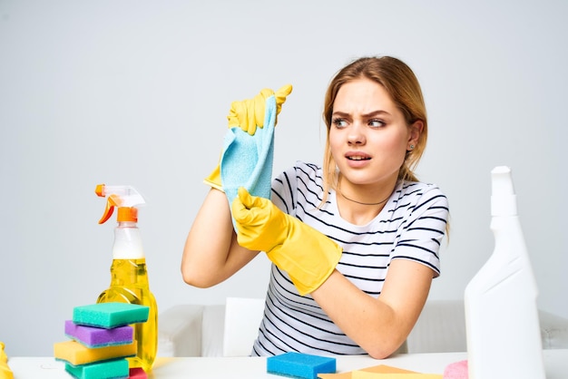 Cleaning lady sitting at the table washing supplies work pallets light background