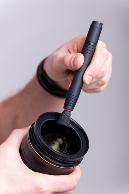 Cleaning the lens. Cropped image of man cleaning a camera lens with lens brush while isolated on white