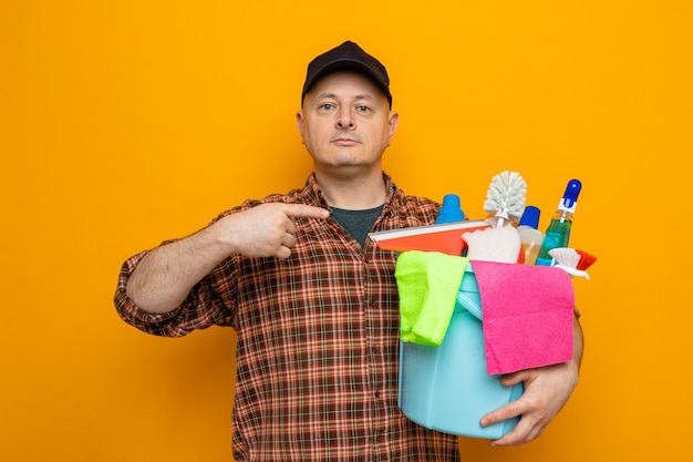 Cleaning man in plaid shirt and cap holding bucket with cleaning tools