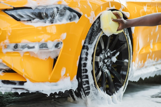 Photo cleaning of modern rims of luxury yellow car at self car wash service outdoors