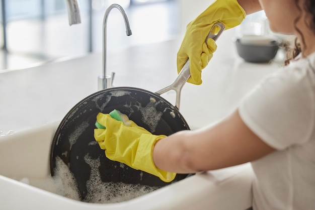 Очистка кастрюли, мытье и гигиена рук с мылом и водой в кухонной раковине дома. Увеличение женской руки и бактерий для дезинфекции, защиты и предотвращения распространения микробов с помощью жидкой пены.