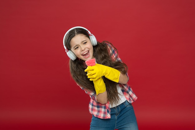 청소 파티. 소녀는 청소를 위해 헤드폰과 보호 장갑을 착용합니다. 음악을 듣고 집을 청소합니다. 재미. 가정을 더 즐겁게 만드십시오. 간단한 재료로 무해한 세정제.