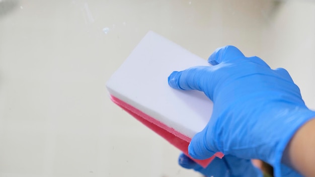 Cleaning person cleaning bathroom glass with gloves and scouring pad