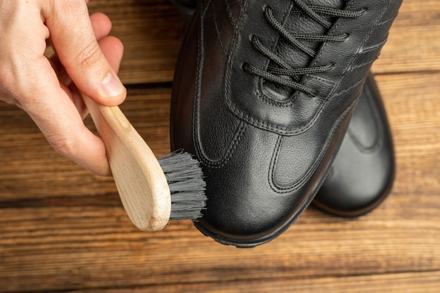 Foto pulizia lucidatura restauro stivali in pelle nera con spazzola e lucido da scarpe