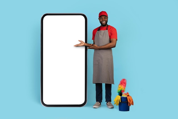 Cleaning service ad black man wearing apron pointing at big blank smartphone