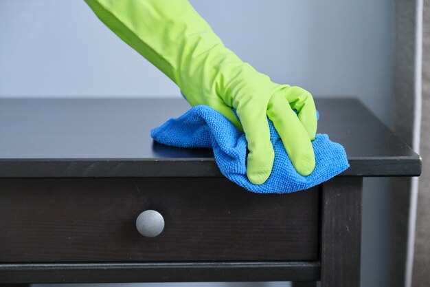 Cleaning service, close-up of gloved hands with microfiber cloth wiping dust