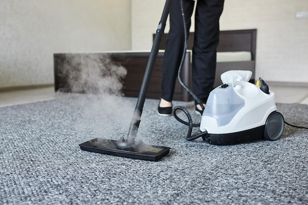 Cleaning service company employee removing dirt from carpet in flat with professional steam cleaner equipment close up