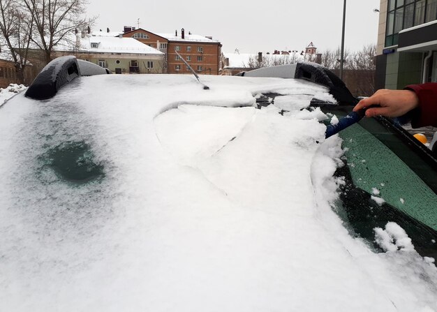 Cleaning snow and frozen ice from windshield Winter car front windows clean