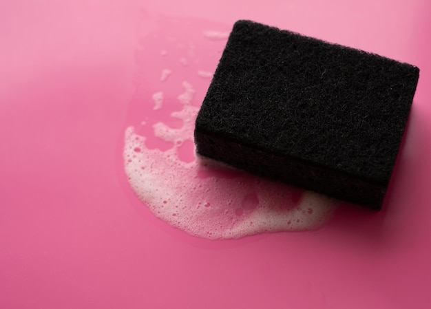 Cleaning sponge and a soapy foam on a pink background Cleaning concept cleaning serviceTop view