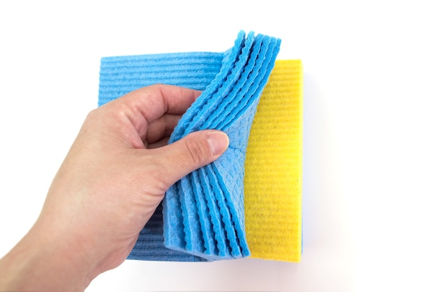 집안의 청결을 유지하면서 흰색 표면에 손에 스폰지를 청소하십시오. 확대.