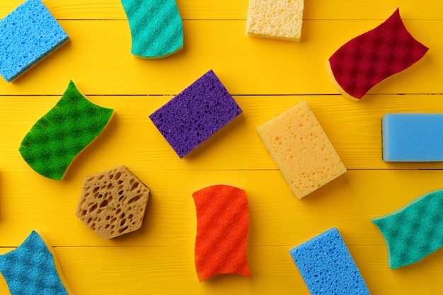 Cleaning sponges on yellow wooden background flat lay