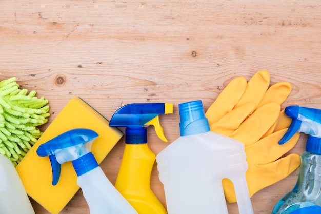 Cleaning spray bottles and cloth lay flat composition on a wooden background