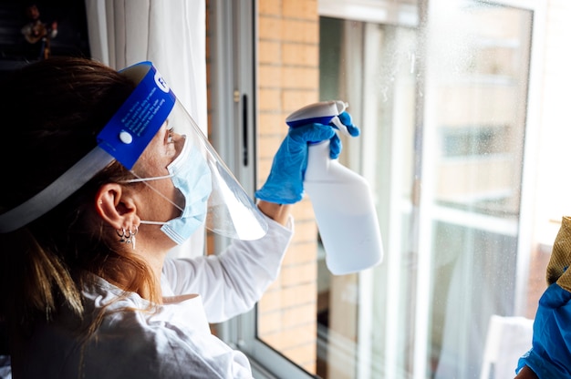 Cleaning staff disinfecting the house against virus, wearing transparent protective mask