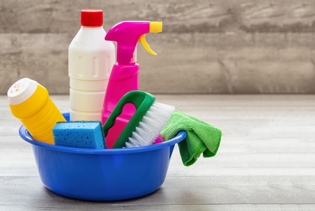 Cleaning supplies in a blue bowl wooden floor background