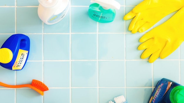 Cleaning supplies on blue tiles background Cleaning gloves cleaning brush and cleaning sprays arranged neatly Bright cleaning tools for effective cleaning Cleaning supplies pastel background