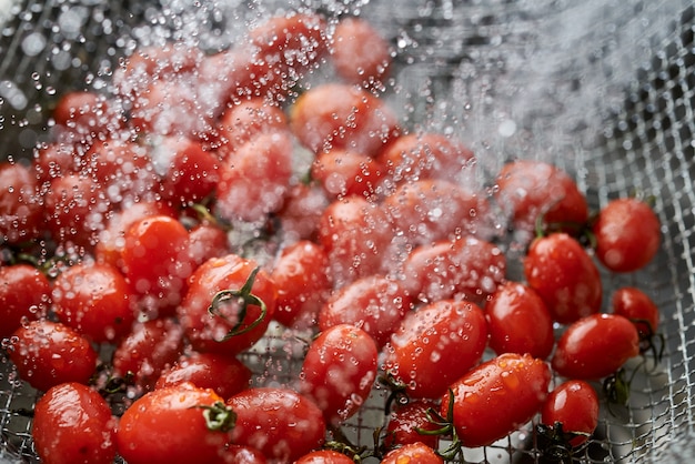 写真 金属ワイヤーバスケットで鮮やかな赤い完熟トマトを掃除する