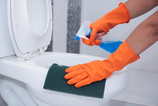 Cleaning toilet bowl with spray and scrub the dirt