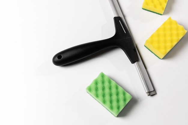Foto strumenti per la pulizia, raschietto, bocchetta per finestre e salviette colorate su sfondo bianco