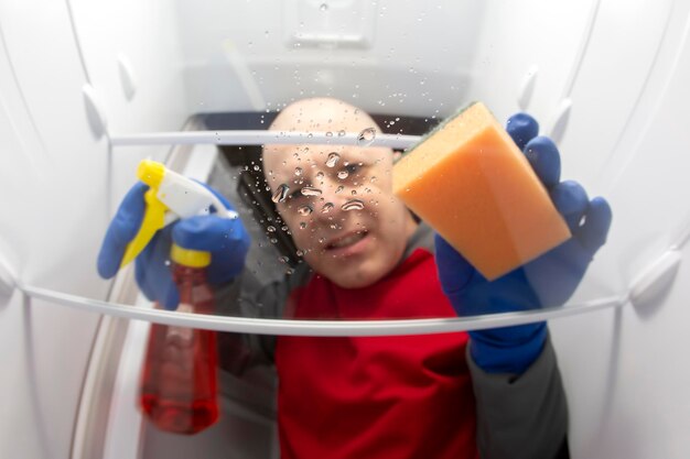 Pulizia e lavaggio interno del frigorifero con spray detergente e spugna servizio professionale per la disinfezione delle attrezzature da cucina per la conservazione degli alimenti