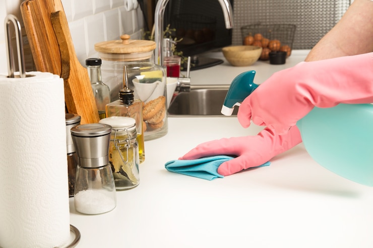 Photo cleaning a white kitchen countertop with a sponge cloth and detergent