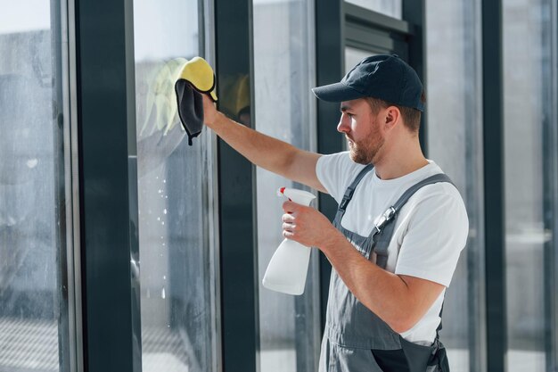 Cleaning window by using special liquid repairman is working\
indoors in the modern room