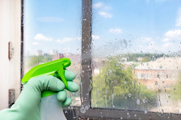 Pulizia finestra con lavaggio finestre con una siringa speciale, spray sul cielo blu servizio di pulizia.