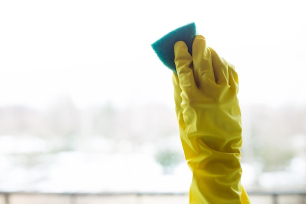 Cleaning windows with special rag and detergent in yellow gloves at house