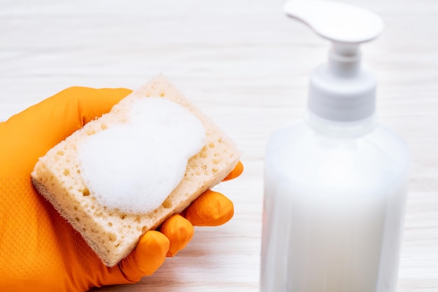 Cleaning with sponge composition with female hands in glove and sponge with foam on tiles surface