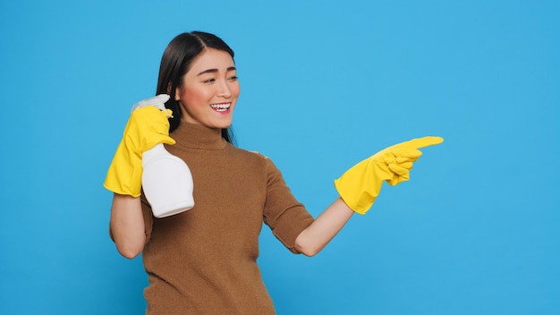 청소하는 여성은 표면을 소독하고 세균의 확산을 방지하기 위해 위생 용액으로 채워진 스프레이 병을 사용하여 청소 제품이나 격리된 텍스트를 가리키고 표시합니다. 대청소 개념